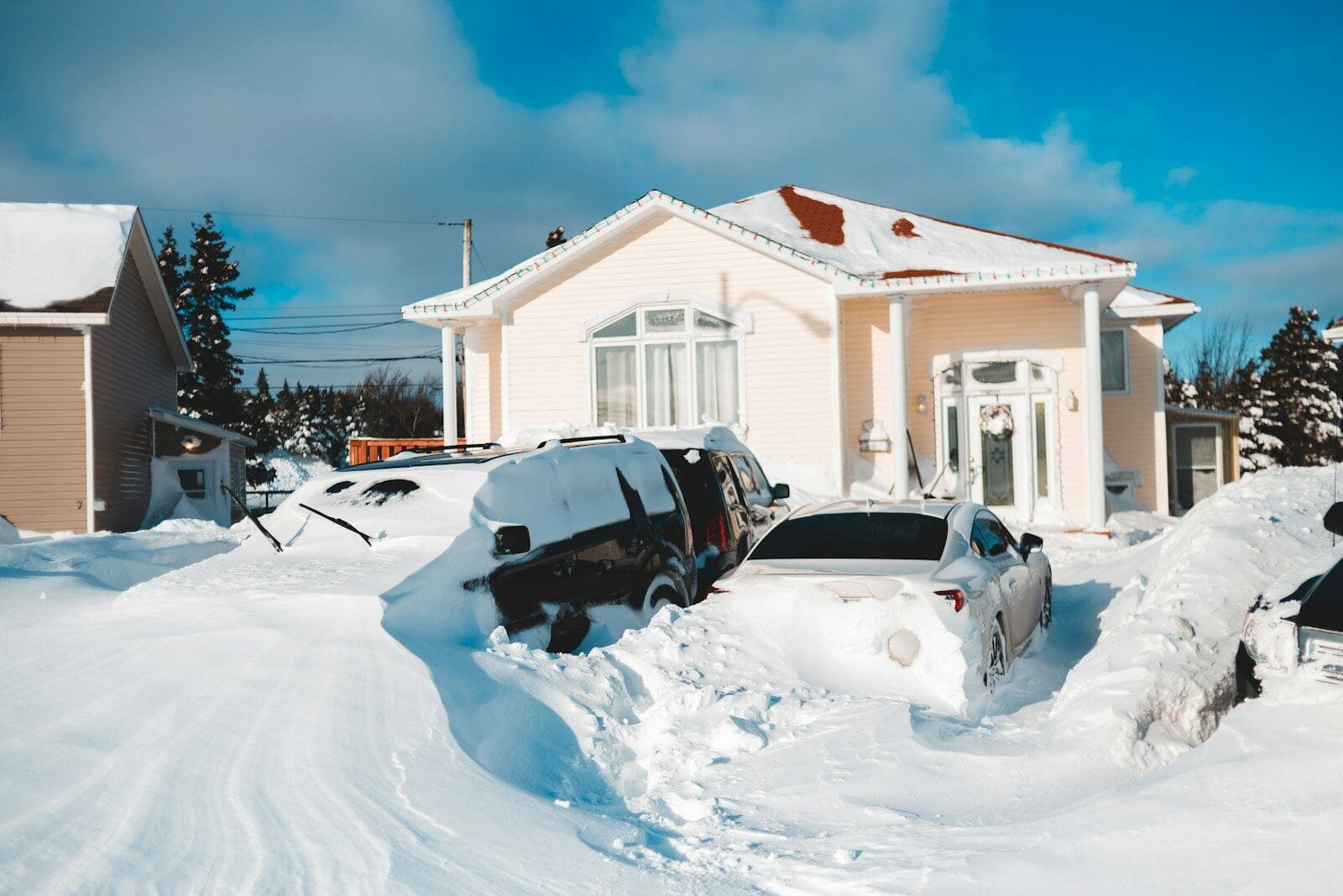 a car is buried in snow in front of a house